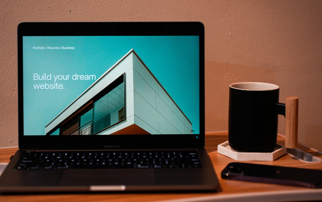 Create the website you’ve always envisioned for your future. A laptop, MacBook, sitting on a portable table with a coffee or tea mug beside it.